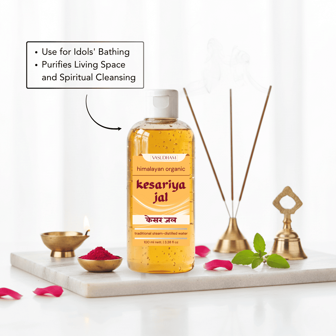 A bottle of Vasudham Kesariya Jal (Himalayan Organic Sacred Floral Water) displayed on a white marble tray with decorative bath accessories, pink petals, and a text box explaining its benefits.