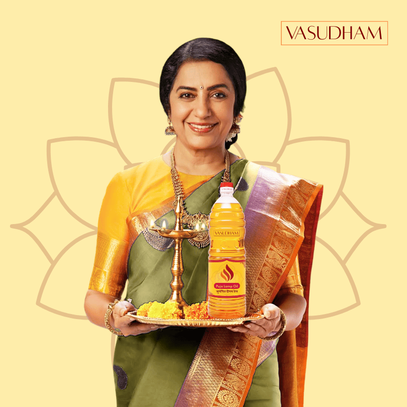 Woman in traditional attire holding a bottle of 'Vasudham' deepam oil with a decorative background