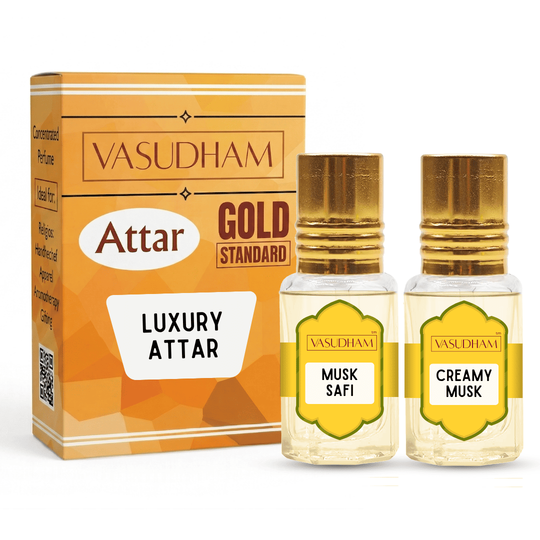 Vasudham Attar Luxury Attar set featuring a gold and orange packaging box alongside two small glass perfume bottles with gold caps, labeled 'Musk Safi' and 'Creamy Musk'.