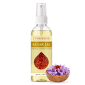 A 100 ml bottle of Vasudham Kesar Jal Premium Saffron Water, featuring a white spray cap and a label with saffron threads. It is displayed next to a small wooden bowl filled with purple saffron flowers on a clean white background.