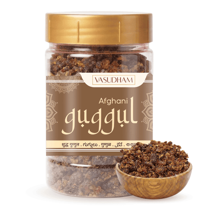 A jar of Vasudham Afghan guggul herbal powder with a gold lid and brown label, shown alongside a small wooden bowl filled with the dark brown powder on a white background.