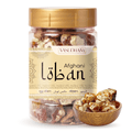 A clear plastic jar of Vasudhami Afghani loban with a gold lid and beige label, shown alongside a small wooden bowl of the mixed nuts on a white background.
