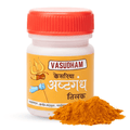 A white plastic bottle of Vasudham Kesarya Aastgandh Tilak with a bright orange-red cap and a yellow-orange label, shown with a small pile of orange-red powder in front on a white background.