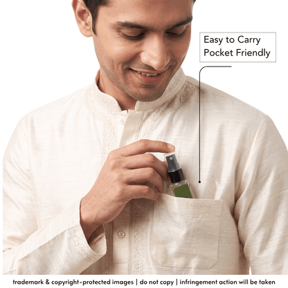 A man in a cream-colored kurta demonstrates a small green spray bottle fitting into his chest pocket, with text overlay reading 'Easy to Carry Pocket Friendly'.