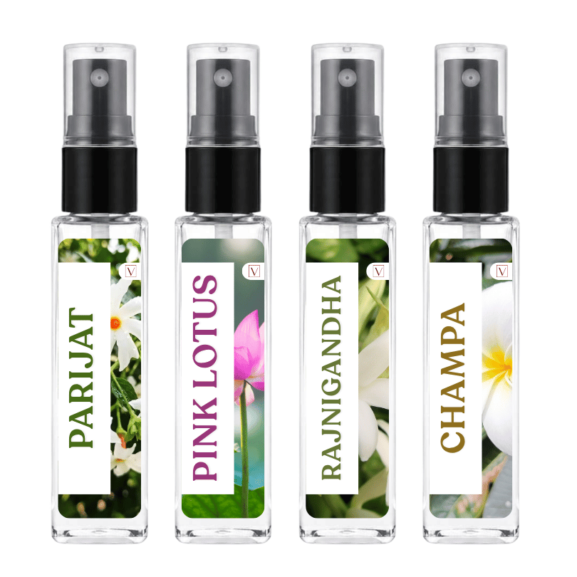 Four clear glass perfume atomizer bottles with black spray pumps, shown side by side on a white background. Each bottle has a floral label with green, pink, white, and gold text reading PARIJAT, PINK LOTUS, RAJNIGANDHA, and CHAMPA.