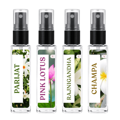 Four clear glass perfume atomizer bottles with black spray pumps, shown side by side on a white background. Each bottle has a floral label with green, pink, white, and gold text reading PARIJAT, PINK LOTUS, RAJNIGANDHA, and CHAMPA.