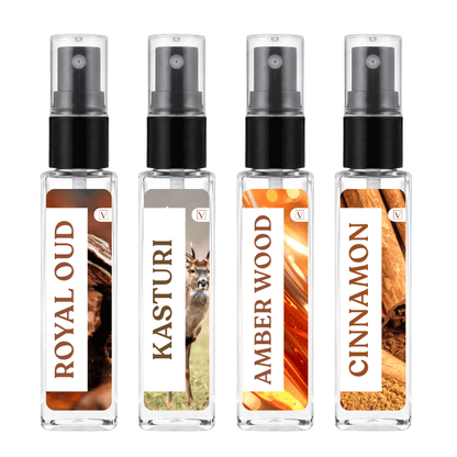 Four clear glass perfume spray bottles with black pump caps, shown side by side on a white background. The labels read ROYAL OUD, KASTURI, AMBER WOOD, and CINNAMON, with warm amber and brown scent imagery on the bottles.
