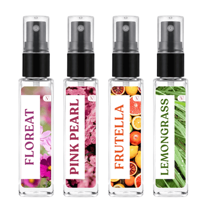 Four clear glass spray bottles with black pumps and clear caps, arranged side by side on a white background. Each bottle has a vertical white label with a different scent illustration: FLOREAT with pink flowers, PINK PEARL with pink blossoms, FRUTELLA with citrus fruits, and LEMONGRASS with green leaves.