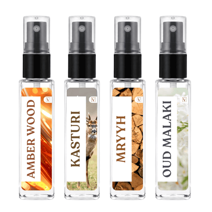 Four clear glass perfume atomizer bottles with black spray tops and white labels, shown side by side on a white background. The labels read AMBER WOOD, KASTURI, MRYYH, and OUD MALAKI, with different natural-themed graphics behind the text.