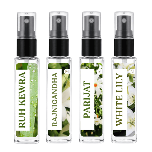 Four small clear spray bottles with black pump tops arranged side by side on a white background. Each bottle has a vertical label with green text and floral/leaf imagery: 'RUH KEWRA', 'RAJNIGANDHA', 'PARIJAT', and 'WHITE LILY'.