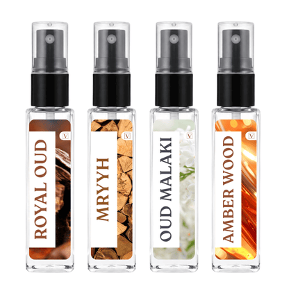 Four clear glass perfume sample spray bottles with black atomizers and white labels, arranged side by side on a white background. The labels read ROYAL OUD, MRYYH, OUD MALAKI, and AMBER WOOD, with warm-toned wood and floral imagery on the bottles.