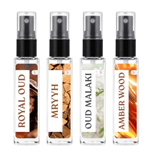 Four clear glass perfume sample spray bottles with black atomizers and white labels, arranged side by side on a white background. The labels read ROYAL OUD, MRYYH, OUD MALAKI, and AMBER WOOD, with warm-toned wood and floral imagery on the bottles.
