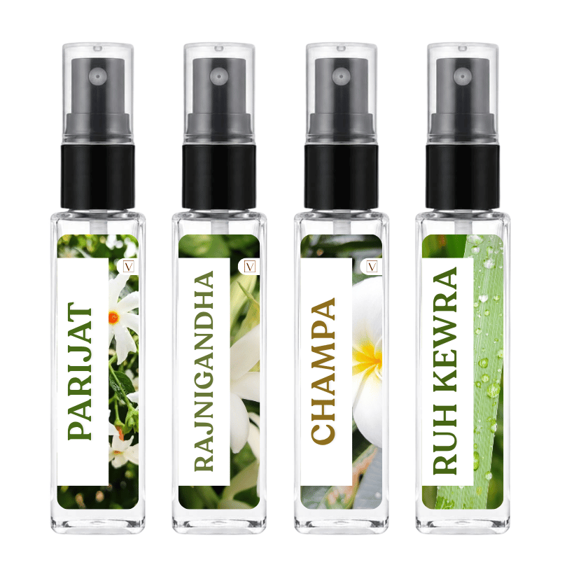 Four clear glass perfume atomizer bottles with black spray nozzles, arranged side by side on a white background. Each bottle has a white label with green and gold text and a floral or natural print: PARIJAT, RAJNIGANDHA, CHAMPA, and RUH KEWRA.