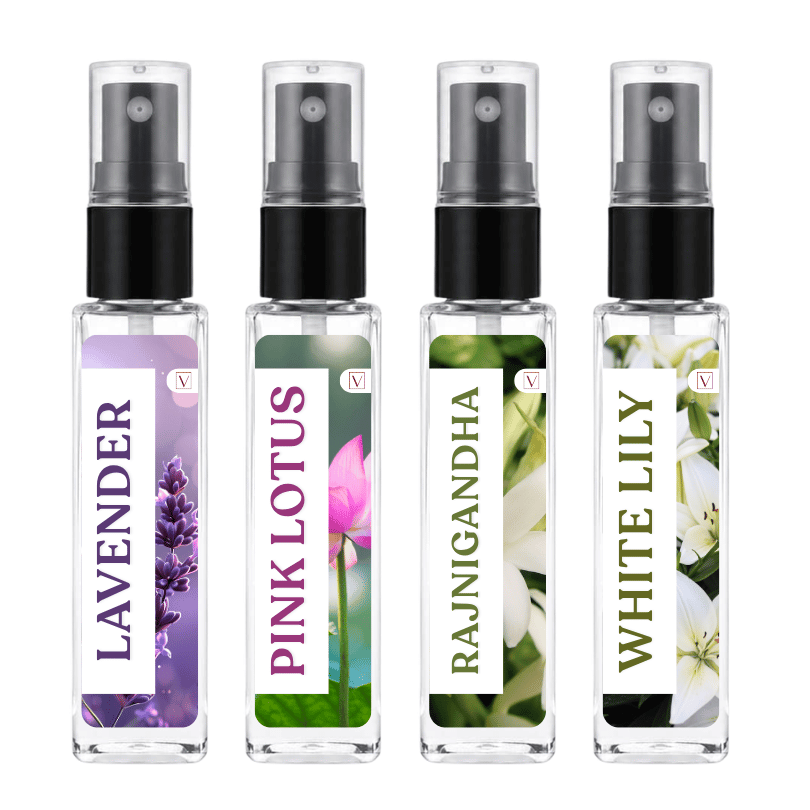 Four clear glass perfume atomizer spray bottles with black spray tops, shown side by side on a white background. The bottles feature floral labels for Lavender, Pink Lotus, Rajnigandha, and White Lily.