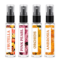 Four clear glass perfume spray bottles with black pumps and clear caps, arranged side by side on a white background. Each bottle has a colorful fruit and flower label with the names FRUTELLA, PINK PEARL, ORCHIDS, and AMBROSIA printed vertically.