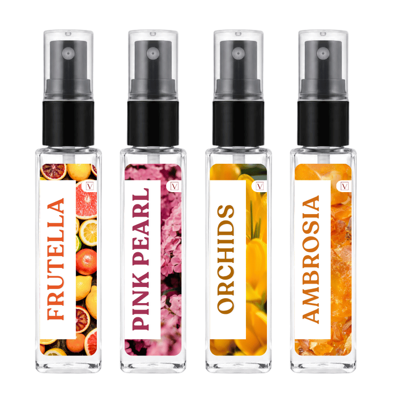 Four clear glass perfume spray bottles with black pumps and clear caps, arranged side by side on a white background. Each bottle has a colorful fruit and flower label with the names FRUTELLA, PINK PEARL, ORCHIDS, and AMBROSIA printed vertically.