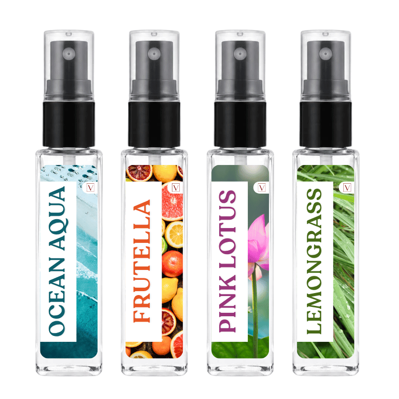 Four clear glass perfume atomizer bottles with black spray tops on a white background. The labels read OCEAN AQUA, FRUTELLA, PINK LOTUS, and LEMONGRASS, with tropical and botanical graphics.