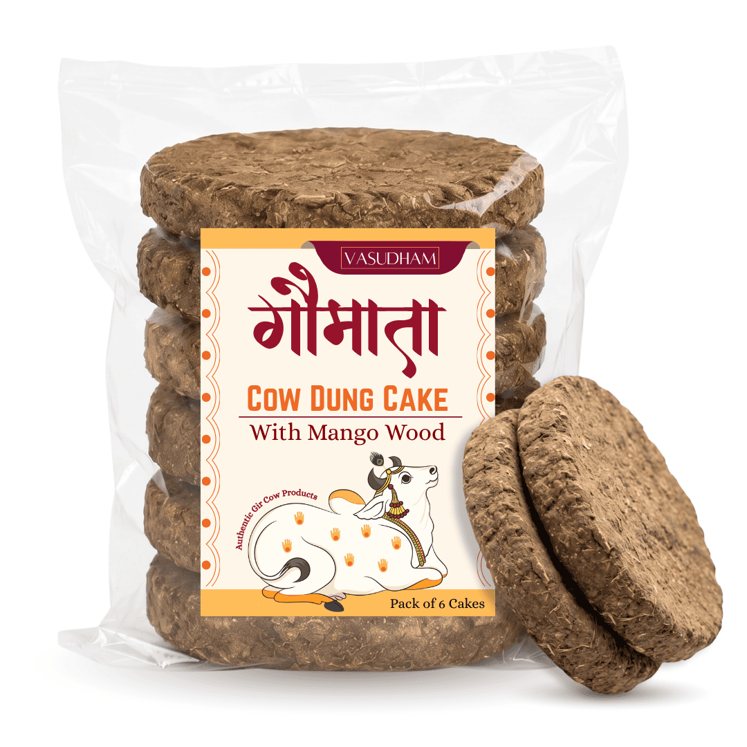 A clear plastic bag containing six round brown cow dung cakes stacked vertically, with two cakes leaning in front. The front label reads VasudhamI' and 'GOOMATA COW DUNG CAKE With Mango Wood'.
