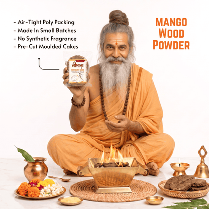 An elderly man with a long gray beard and hair in a bun, dressed in orange robes, holds up a jar of Mango Wood Powder. The scene is set on a white background with traditional Indian elements, including a brass incense burner with flames, a copper pot, marigolds, and cookies.