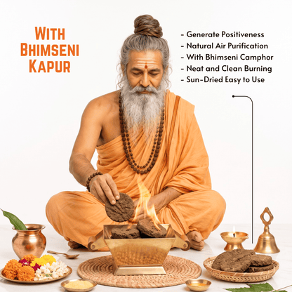 An elderly man with a long gray beard and hair in a bun sits cross-legged on a white studio background, performing a ritual with Bhimseni kapur. He is dressed in orange robes and is surrounded by offerings, a brass incense burner with visible flames, decorative brass vessels, and text overlays describing the product benefits.