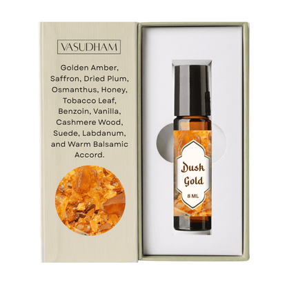 Vasudham Dush Gold 8ml roll-on bottle with amber liquid, presented in a white box next to its beige packaging insert detailing the scent notes and ingredients.