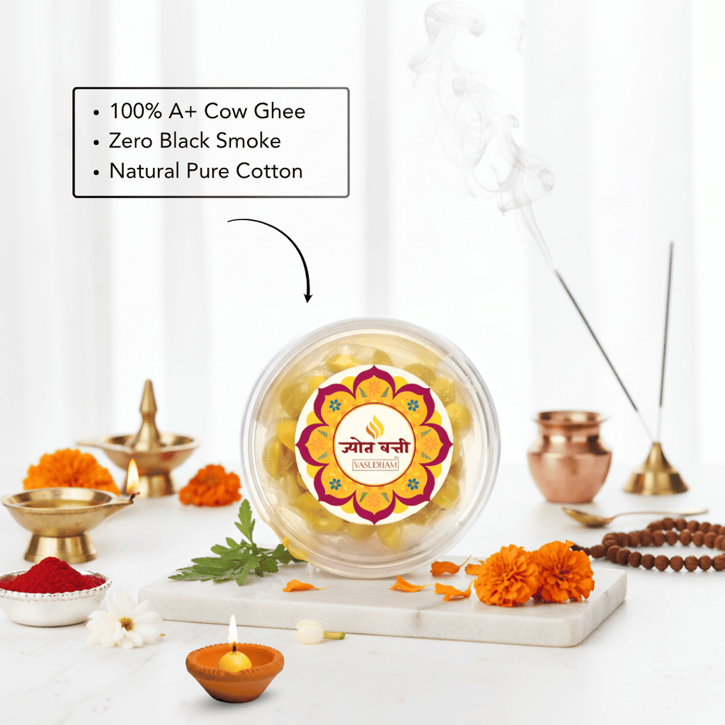 A clear round jar of Ghee Ganesha idol wax beads sits on a marble tray, surrounded by ritual props including brass oil lamps, marigolds, incense sticks, and a text callout emphasizing 100% A+ Cow Ghee, Zero Black Smoke, and Natural Pure Cotton.