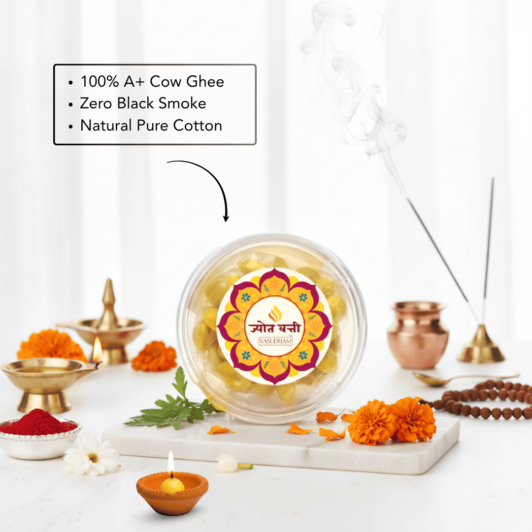 A clear round jar of Ghee Ganesha idol wax beads sits on a marble tray, surrounded by ritual props including brass oil lamps, marigolds, incense sticks, and a text callout emphasizing 100% A+ Cow Ghee, Zero Black Smoke, and Natural Pure Cotton.
