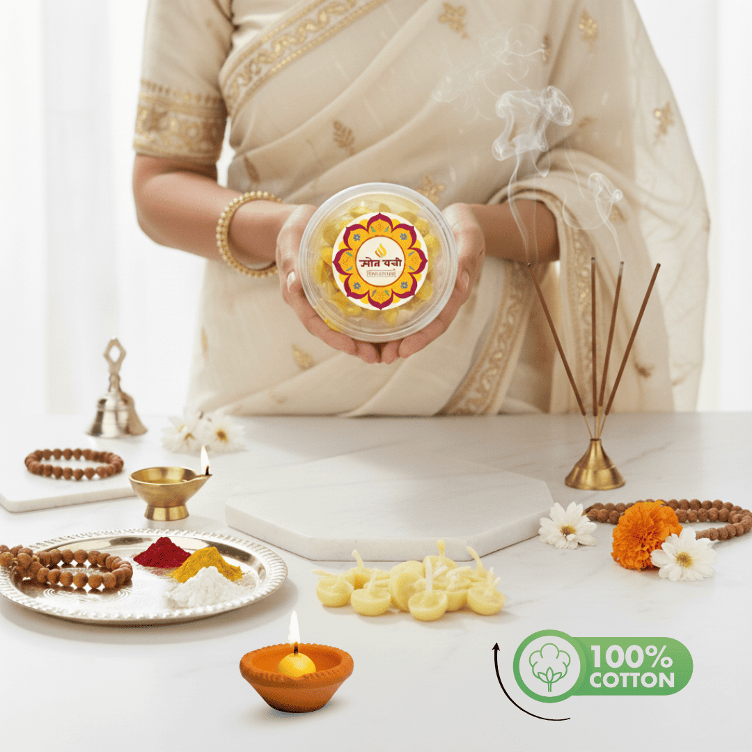 A person in a cream saree holds a round clear plastic container of Gopal Das Golu Idli, surrounded by festive props like a diya, incense, and beads on a white table. A '100% COTTON' badge is in the bottom right corner.