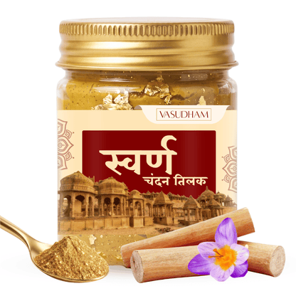 A jar of Vasudham Swarn Chandan Tilak (gold body paint) with a gold-colored lid, shown alongside a gold spoon filled with the powder, wooden sticks, and a purple flower on a white background.