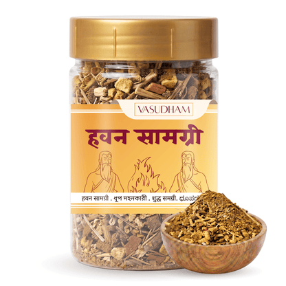 A clear plastic jar of Vasudham Havan Samagri herbal powder with a gold lid and a yellow label, shown alongside a small wooden bowl filled with the dried herbal mixture on a white background.