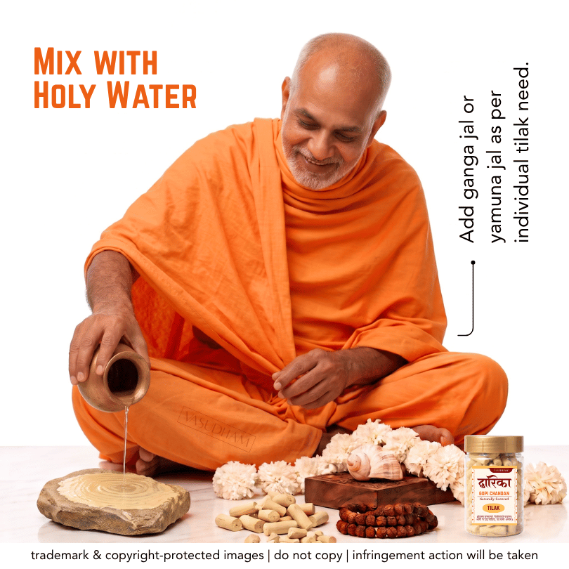 A man in an orange robe sits cross-legged on a white background, pouring holy water from a small clay pot. In front of him are flowers, a wooden slice, beads, and a jar labeled 'Shree Vallabha'.