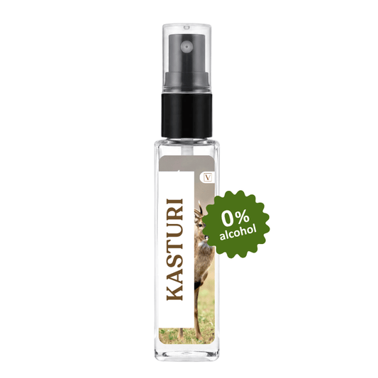 A clear glass spray bottle with a black pump dispenser and a white label featuring the brand name 'KASTURI' vertically. The label includes a photo of a deer and a green starburst badge that reads '0% alcohol'.