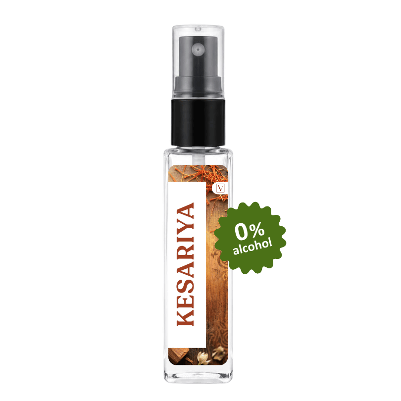 A clear glass perfume spray bottle with a black pump and a white label featuring the brand name 'KESARIYA' in brown text. The label also shows botanical imagery and a green starburst badge that reads '0% alcohol'.