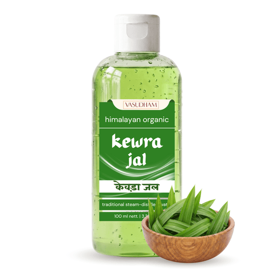 A 100 ml bottle of VASDUHAM Himalayan Organic Kewra Jal (himalayan cold water) with a white cap, shown next to a small wooden bowl filled with fresh green aloe vera leaves on a white background.