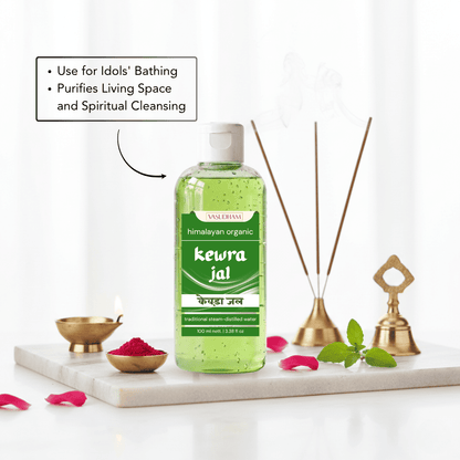 A bottle of Kewra Jal Himachal Organic bath liquid is displayed on a white marble tray with decorative bath props including brass oil lamps, incense sticks, mint leaves, and pink petals. A text box on the left highlights its benefits for cleansing.
