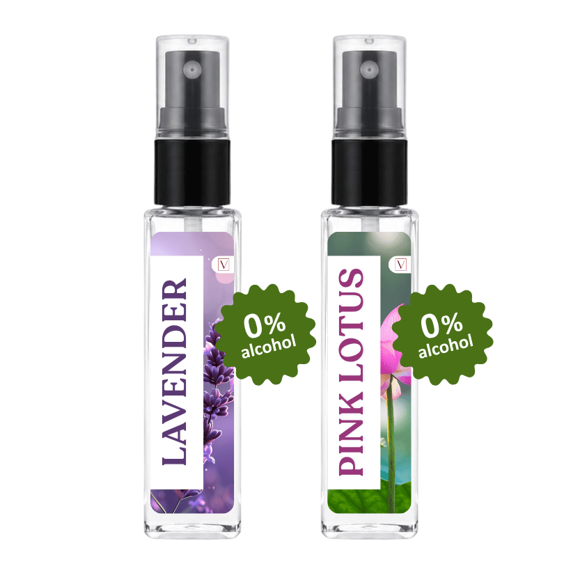 Two small clear spray bottles with black pump tops on a white background. The left bottle has a lavender floral label and the right bottle has a pink lotus floral label.
