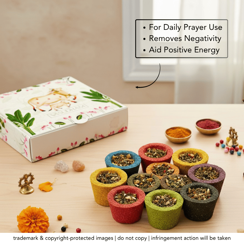 A set of colorful cylindrical prayer beads or amulet holders arranged on a light wooden table, with a floral gift box, small bowls of powder, decorative beads, and an informational text box in the background.
