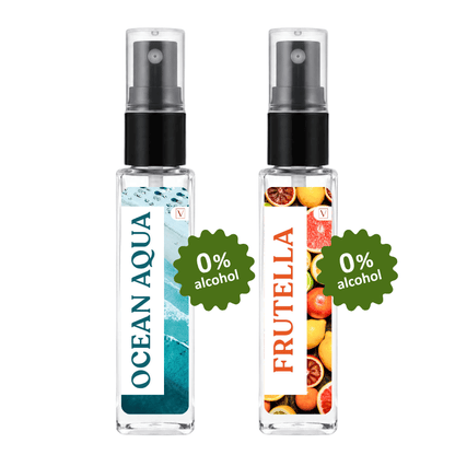Two clear glass perfume spray bottles with black pumps on a white background. The left bottle has a blue and white wave label reading 'OCEAN AQUA' and a green badge that says '0% alcohol'.