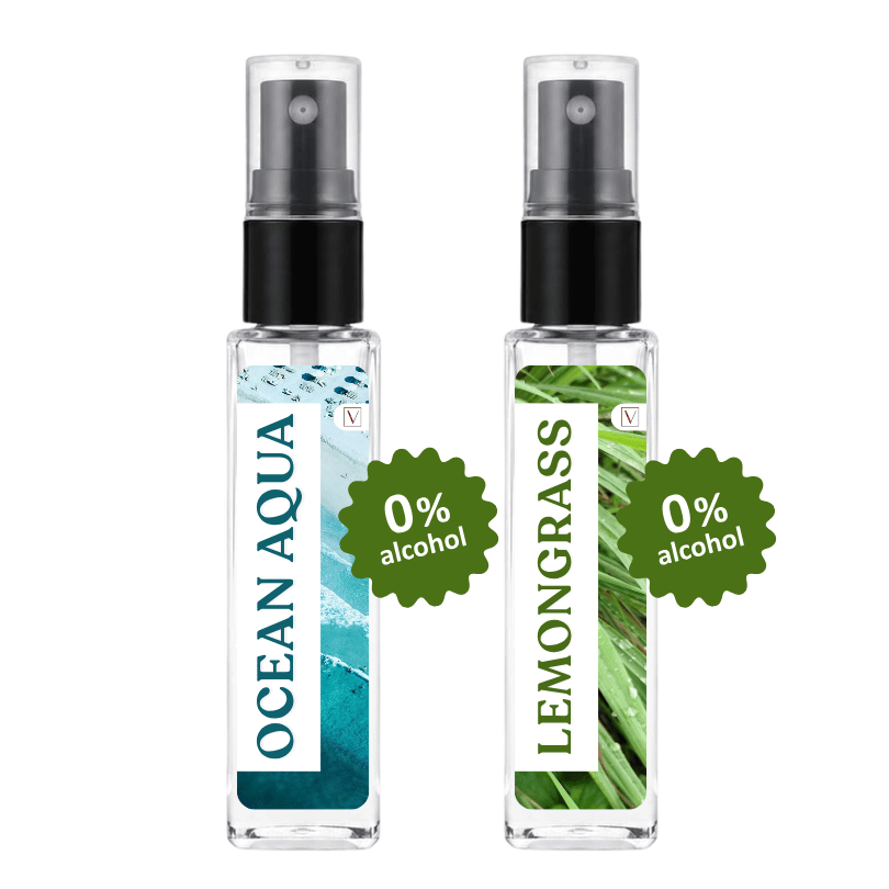 Two clear glass spray bottles with black pump tops on a white background. The left bottle has a blue ocean wave label reading OCEAN AQUA, and the right bottle has a green leafy label reading LEMONGRASS.