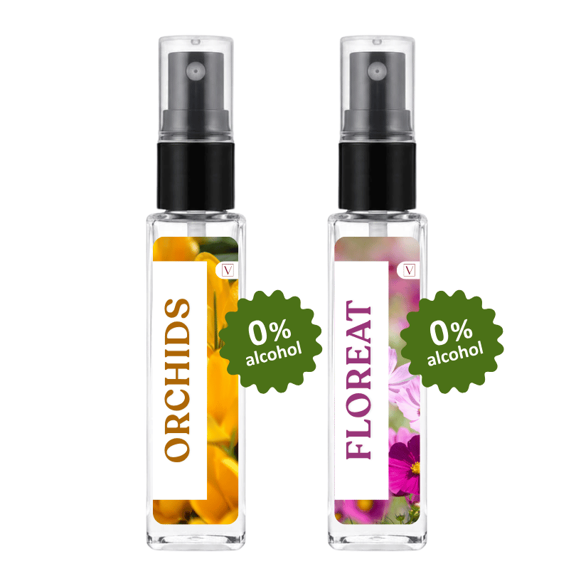 Two clear glass perfume spray bottles with black atomizers on a white background. The left bottle is labeled ORCHIDS with yellow/orange floral imagery and a green '0% alcohol' badge.
