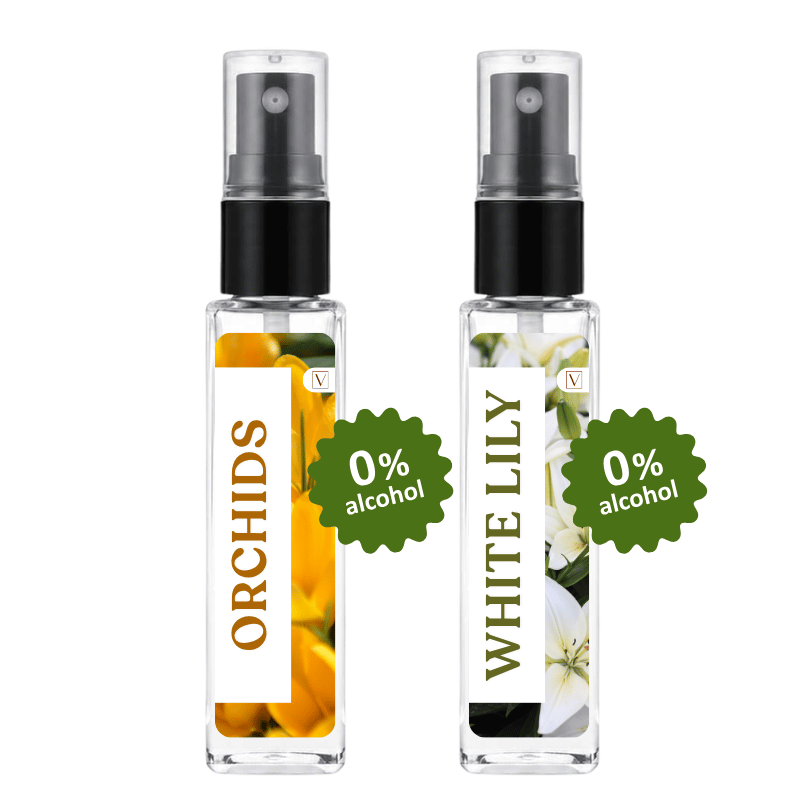 Two clear glass perfume spray bottles with black pumps on a white background. The left bottle has a white label with orange orchid flowers and the word ORCHIDS, with a green burst reading 0% alcohol.
