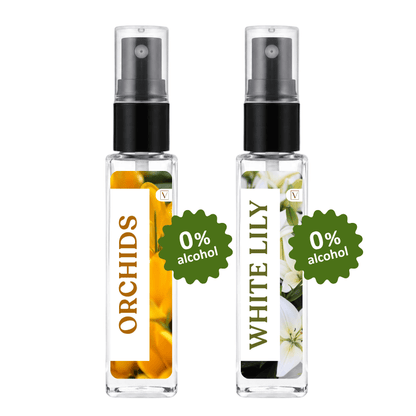 Two clear glass perfume spray bottles with black pumps on a white background. The left bottle has a white label with orange orchid flowers and the word ORCHIDS, with a green burst reading 0% alcohol.