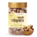 A jar of Vasudham Pahadi Loban (frankincense) with a gold lid and cream-colored label, shown alongside a small wooden bowl of chopped frankincense on a white background.