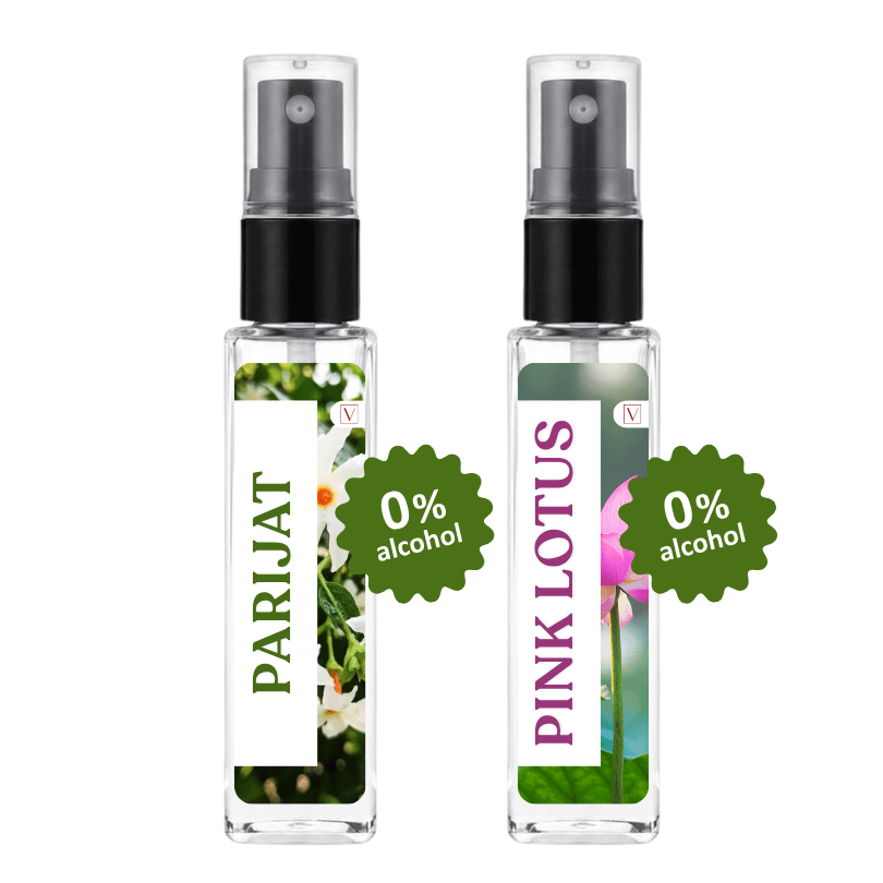 Two clear glass perfume atomizer spray bottles with black spray tops on a white background. The left bottle has a white label with green text reading 'PARIJAT' and a floral photo, with a green badge overlay reading '0% alcohol'.