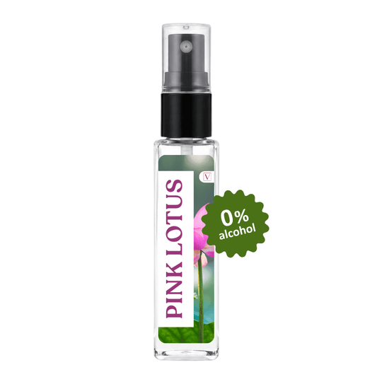 A clear glass perfume or body spray bottle with a black pump, featuring a vertical label that reads 'PINK LOTUS' in pink text over a lotus flower illustration. A green burst sticker on the right says '0% alcohol'.