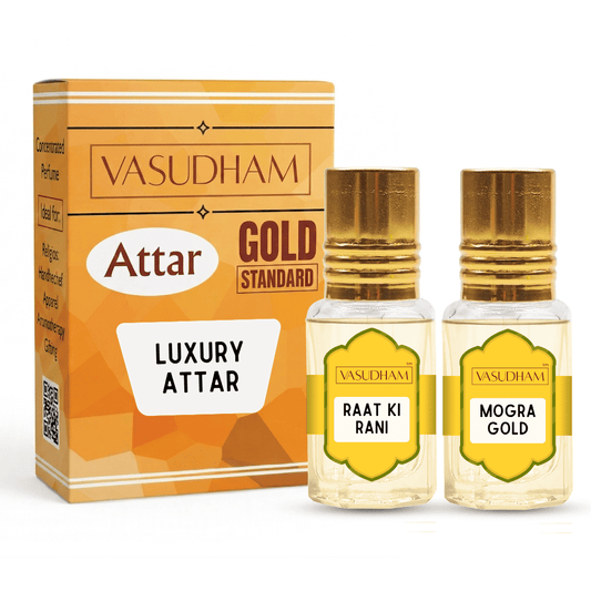 Vasudham Attar Gold Standard Luxury Attar set, featuring a gold and orange box alongside two small glass bottles with gold caps labeled 'Raat ki Raani' and 'Mogra Gold'.