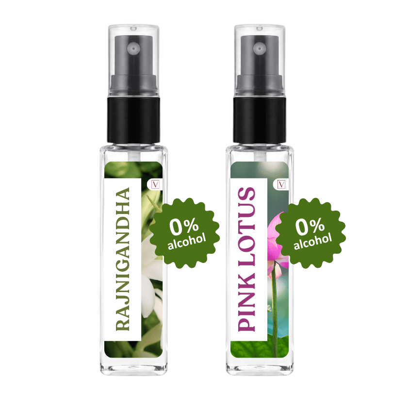 Two clear glass perfume atomizer bottles with black spray tops on a white background. The left bottle has a white label with green text reading RAJNIGANDHA and a white flower photo.