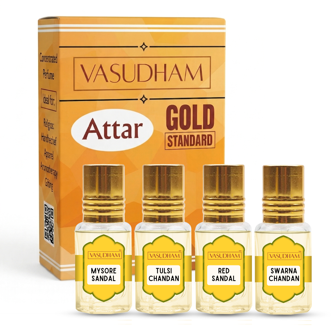 Vasudham Attar Gold Standard perfume set, featuring a large orange and gold box behind four small glass perfume bottles with gold caps and yellow labels: Mysore Sandal, Tulsi Chandan, Red Sandal, and Swarna Chandan.